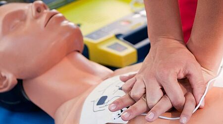 Das Bild zeigt Hände bei der Herzdruckmassage an einer Dummy-Puppe in der Nahaufnahme